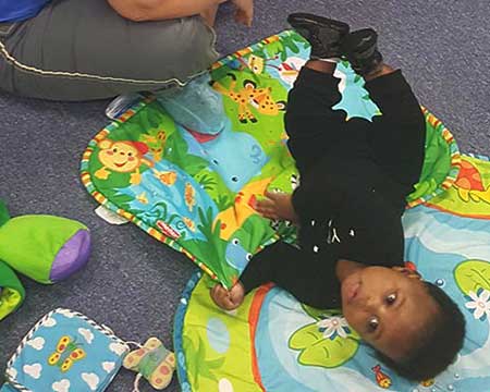 infant laying on a mat